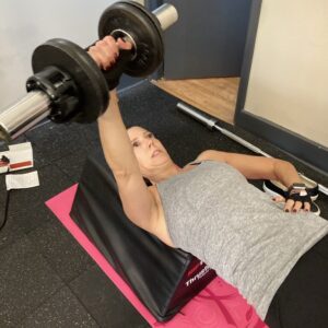 Tina doing one arm dumbbell bench presses in my Boonton personal training studio